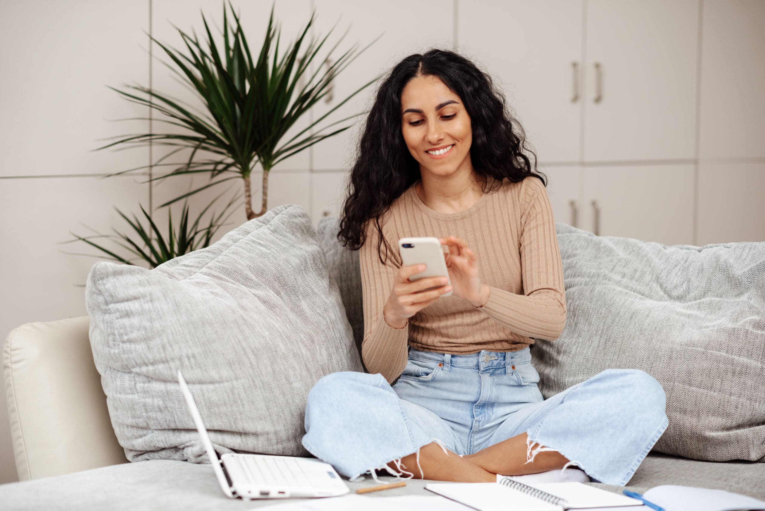 Smiling Millennial Mixed Race Woman Looks At Phone, Reads Messag A woman holding a pregnancy test and a menstrual cycle calendar wondering "How Soon Can I Take a Pregnancy Test?"